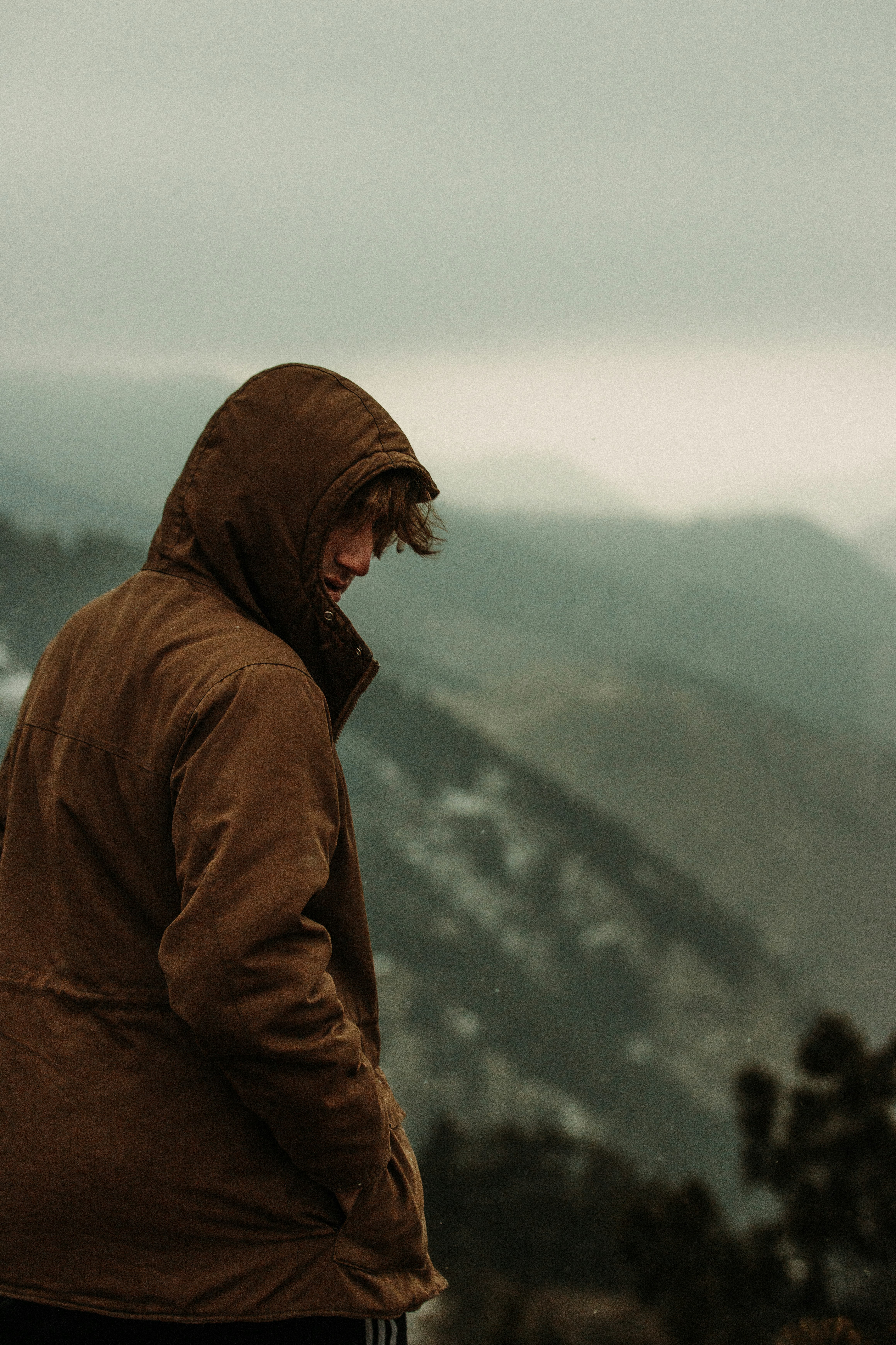 man in brown hoodie standing on snow covered ground during daytime